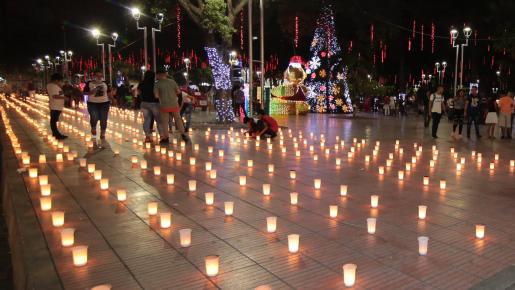 en los parques, plazas, en los frentes de las casas cada familia enciende su velita.